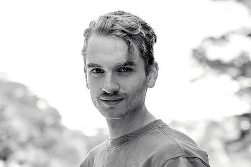 Black and white portrait of 22 years old young man outdoor, background with copy space, full frame horizontal composition