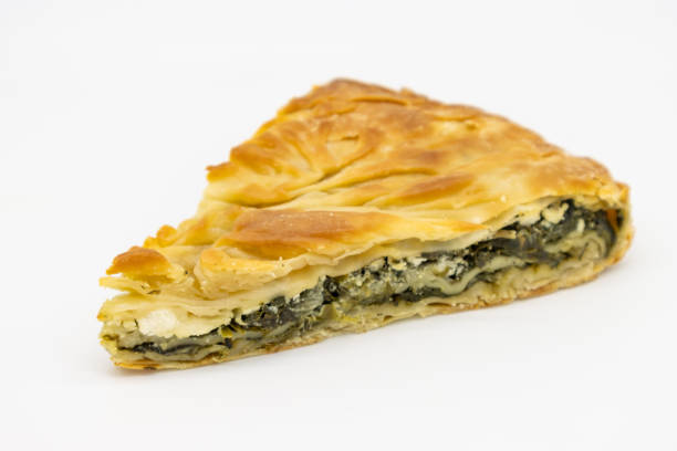 Slice of Greek Spinach Pie Spanakopita on a White Background A closeup of a delicious slice of Greek spinach pie spanakopita on a white background spanakopita stock pictures, royalty-free photos & images