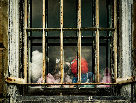 Backside of toys left behind visible through a metal barred window in an abandoned state hospital, West Virginia, USA