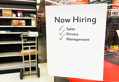 Small business places job seeking work for hire sign on fiberglass window near register.