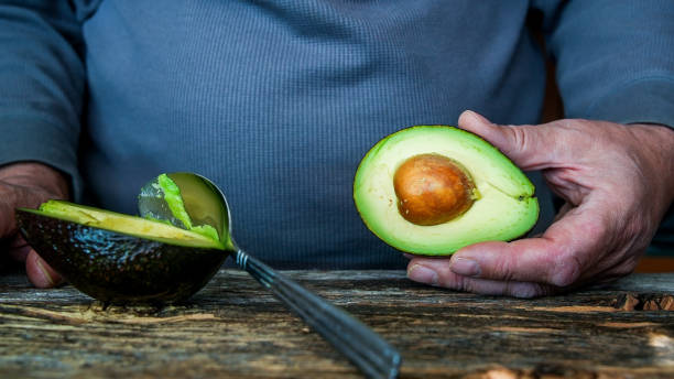 istock Man holding avocado in rustic wooden table 1463226756