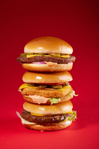 Three delicious burgers on red background. Fast food. Close-up