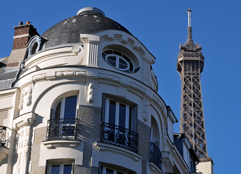 Paris, France, Sept. 26, 2018: The top of the iconic Eiffel Tower rises behind an ornate residential building in Paris.