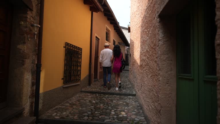 Man and woman couple walk through old cobblestone village enjoying the views