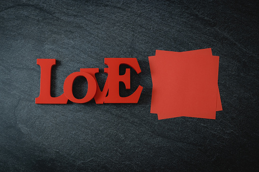 One red wooden solid word love and empty lits lies on a black stone background with copy space, flat lay closeup. The concept of Valentine's Day, love day, black friday.