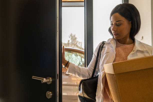 istock Hispanic woman bringing a box through the front door 1463236624
