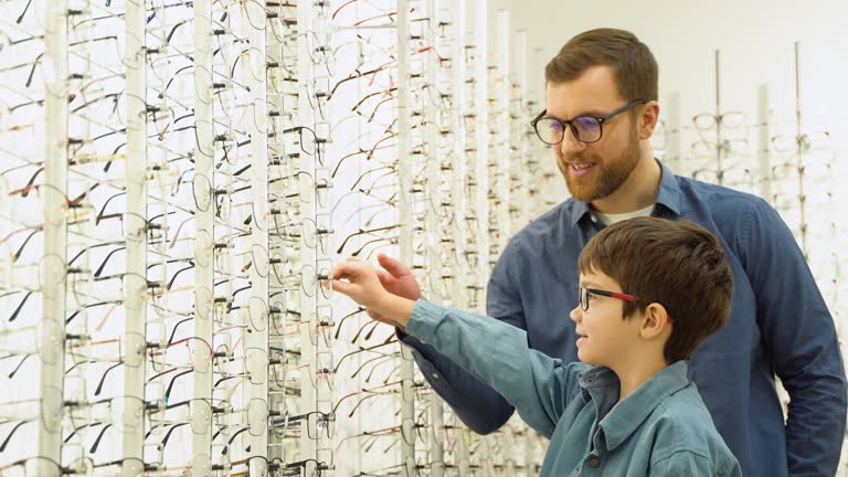 Family buy glasses. Father and son in a blue shirts choosing glasses