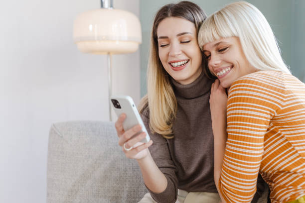 istock Female friends using smart phone at home 1463236694