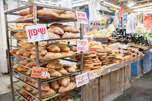 Tel Aviv, Israel - June 17, 2022:  Freshly-baked loaves of bread, bagels, and vegetables for sale at Carmel Market (Shuk Hacarmel), Tel Aviv