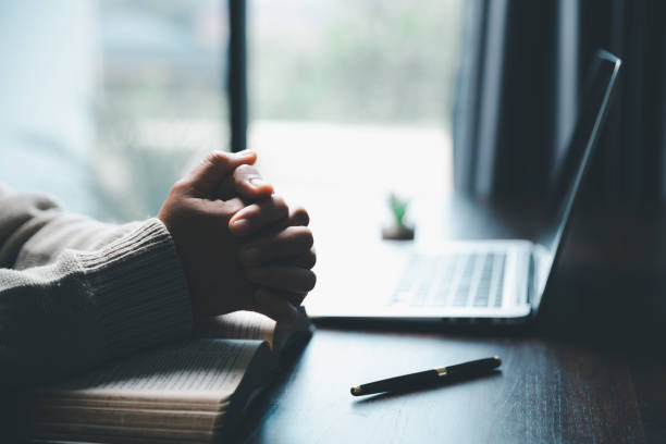 istock Christian online technology concept. Hands praying of christian with digital computer laptop, Online live church for sunday service. Asian catholic woman are reading Holy bible book and online study. 1463247756