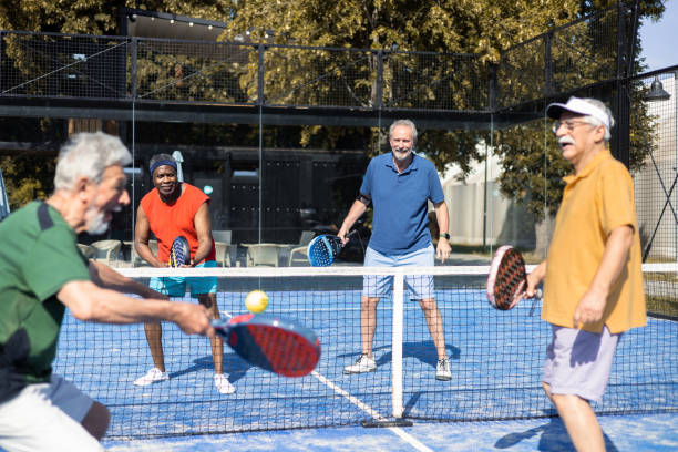 cuatro seniors jugando pickleball en dobles - tennis senior adult adult mature adult fotografías e imágenes de stock