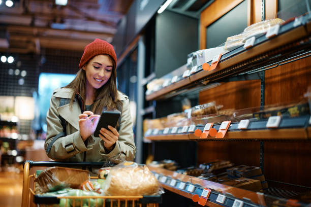 istock Smiling woman text messaging on cell phone while shopping at grocery store. 1463252704