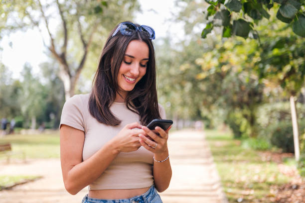 istock smiling woman typing on mobile phone in a park 1463252793