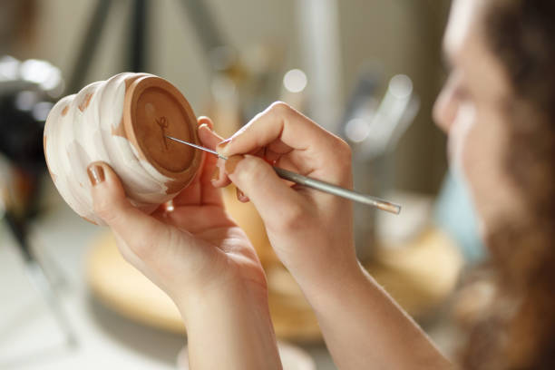 istock Young woman making pottery indoors at creative studio craftsperson concept sitting at table using modeling tool creating details on cup 1463253888