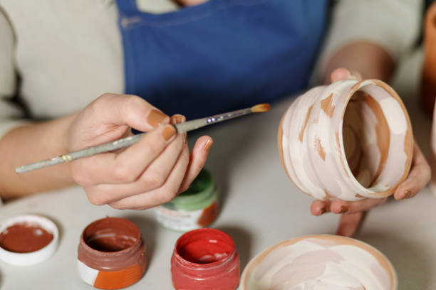 istock Woman hands, pottery studio and painting cup in workshop for sculpture, creative manufacturing or design. Painter, ceramics product and brush process, artistic pattern or production in small business 1463253900