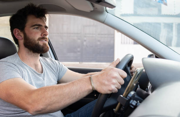 istock young good looking bearded man driving a car, app driver holding the steering wheel using grey shirt 1463258499