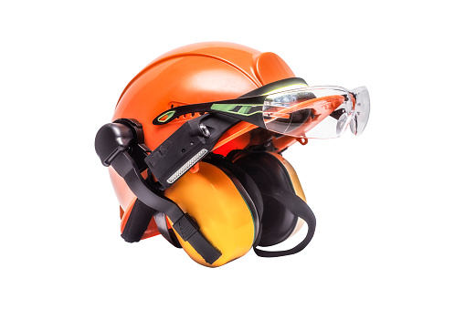Protective goggles for eyes and construction helmet for head with earmuffs and headlamp on white background. Construction tool and form for protection