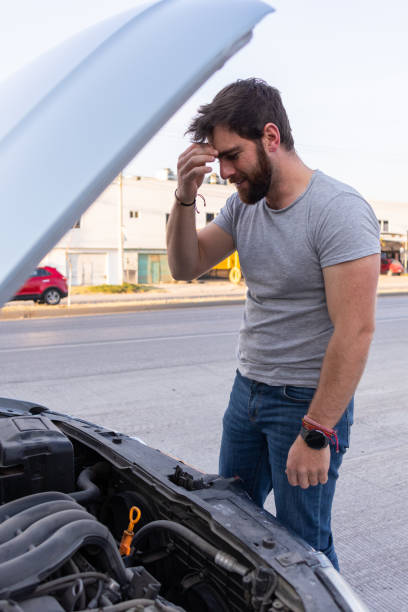 istock worried young man driver checking on the car motor, having problems driving, car insurance concept 1463259275