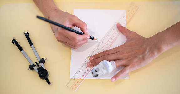 The female hand using a ruler with the pencil prepares to draw and sketch on the empty white paper.