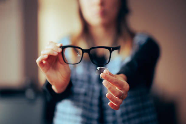 woman holding a broken pair of glasses showing falling lens - broken glasses imagens e fotografias de stock