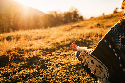 Young boho woman in the nature. Young woman watching the sunrise and meditating in the nature.