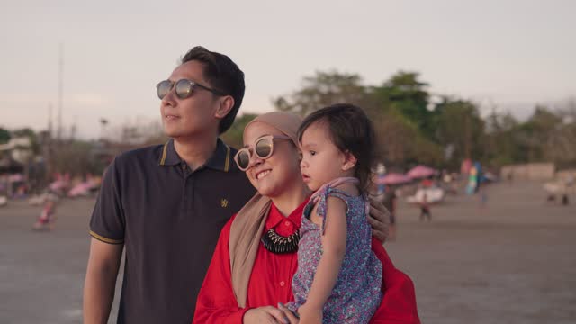 Happy Muslim Indonesian Family Father Mother and Toddler Love Enjoying Sunset Together on The Beach