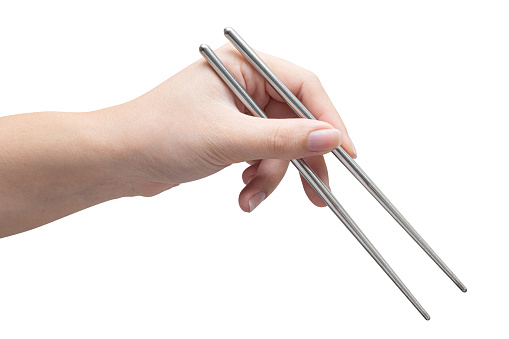 isolated of a woman's hand holding a silver chopstick to pick food.