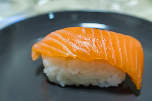 Japanese Omakase meal: Aging Raw Akami Tuna Sushi adds with sliced truffle served by hand on a stone plate. Japanese traditional and luxury meal.