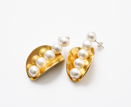 Close-up of gold earrings with pearl on white background.