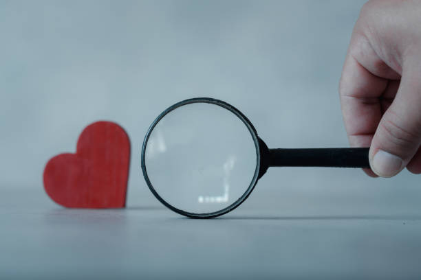 istock Hand holding black magnifying glass to looking for red heart. 1463285295