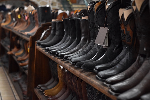 Rows of leather cowboy boots lined up on wooden racks