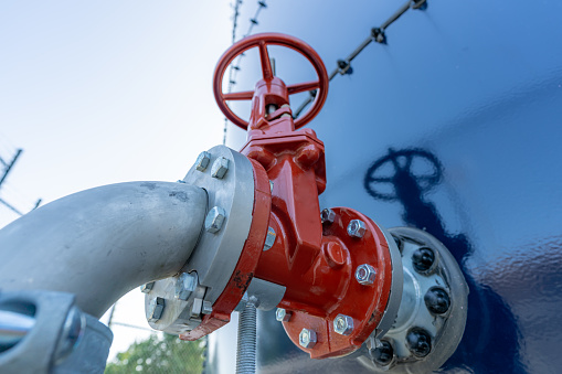 Red water valve on the side of a blue water tank.