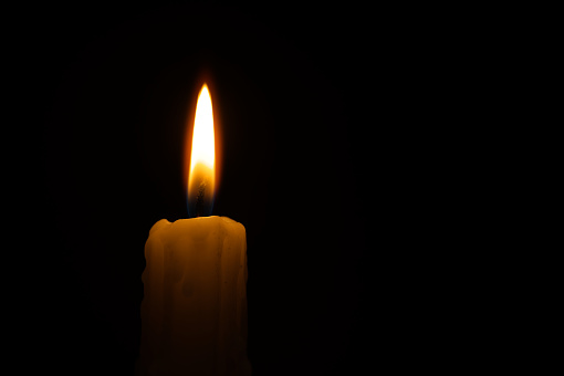 Burning candle against a black background with free copy space for text