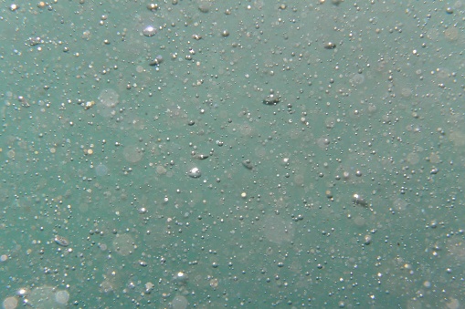 Bubbles of oxygen or air in liquid. Macro. Oxygen bubbles in water, turquoise background, concept of ecology, purity and other related to liquid or water.