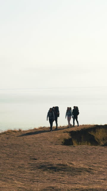The four travelers with backpacks walking on the seascape