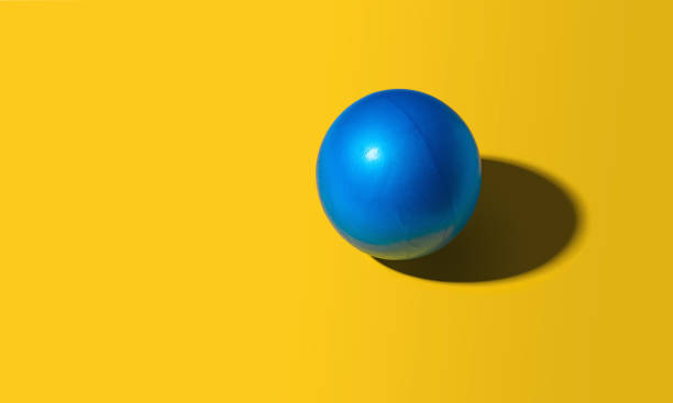 istock Bright blue ball on a yellow background 1463304271