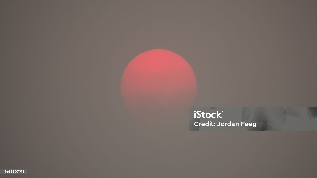 Red Sun in Thick Smoky Polluted Air Red sun caused from air pollution smog and haze. Smoke from forest fires and environment climate change. Forest Fire Stock Photo