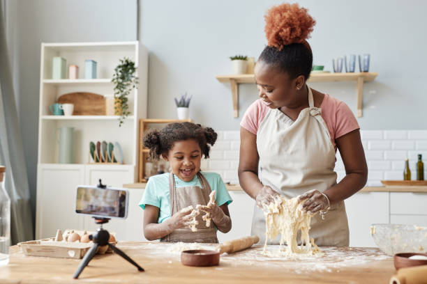 Happy black mother and daughter baking together in home kitchen
