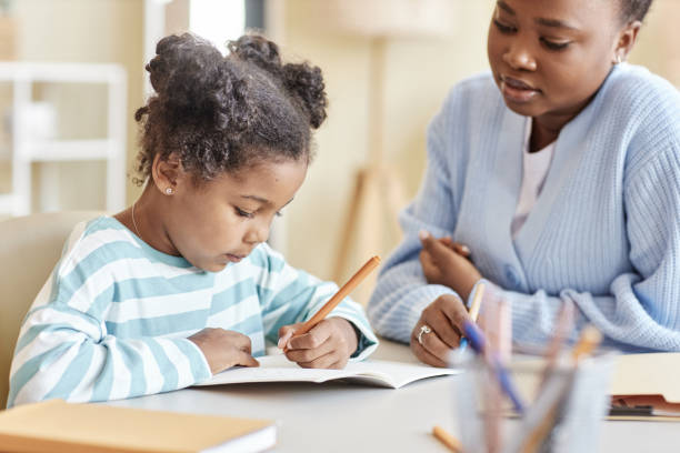 istock Side view cute black girl studying with tutor and writing in notebook 1463319583