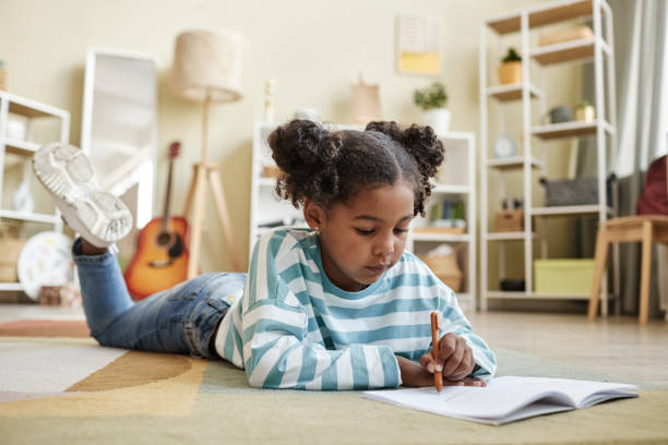 istock Cute black girl laying on floor at home and writing in notebook or diary 1463319601