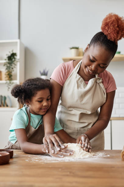 istock Happy black mother and daughter baking together in cozy home kitchen 1463319621