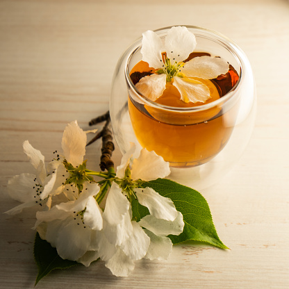 Taza de té transparente con ramas de manzana en flor y sobre un fondo de madera en el lateral. Hora del té. Enfoque selectivo. Taza de té transparente con flores de manzano. photo