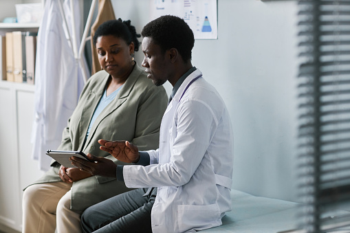 Side view portrait of doctor and patient talking in clinic setting, copy space
