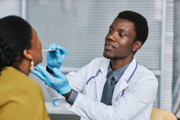 istock Young black doctor examining patient in clinic doing flu check up 1463319943