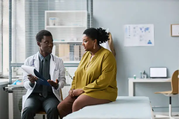 Photo of Overweight black woman talking to doctor in medical clinic