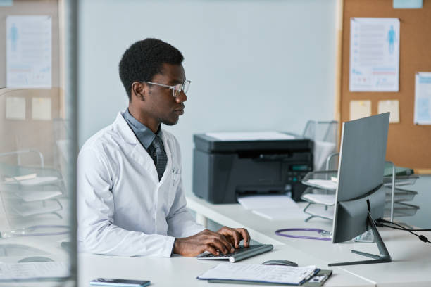 istock Young black doctor using computer at desk in office working in clinic 1463319985