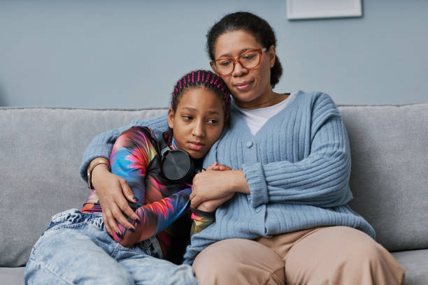Black woman embracing teenage daughter Portrait of mature black woman embracing teenage daughter during bonding moment at home child sadness stock pictures, royalty-free photos & images