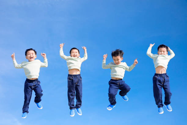 Fröhliches Kind springt und gestikuliert vor blauem Himmel – Foto