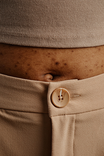 Close up detail shot of womans stomach with focus on skin texture and belly button