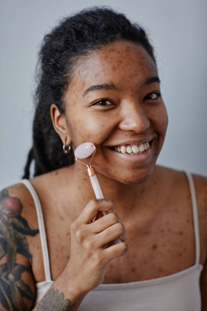 istock Closeup young black woman using face massager and smiling minimal 1463321979